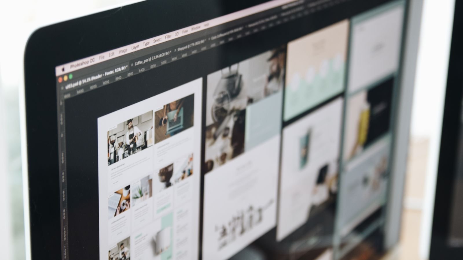 Website design layouts displayed on a desktop monitor